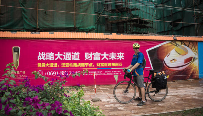 Will inspecting a Chinese billboard announcing a new high speed rail which will pass through the border town of Mohan (photo credit: Kyle Seewald Hemes)