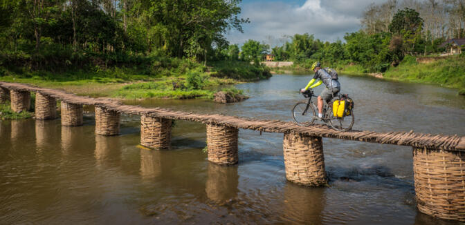 Kyle balances his loaded bike across a bamboo bridge in rural Luang Namtha (photo credit: Will Stauffer-Norris)