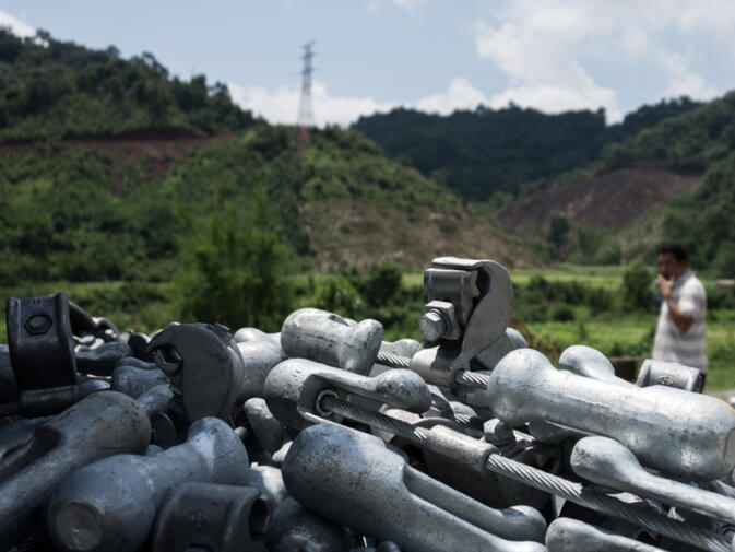 Raw materials piled along the route of the new high voltage power lines going up on the ridge	in Oudomxay Province, Laos (photo credit: Kyle Seewald Hemes)