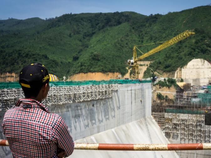 Our boat pilot takes in the new barrier to his traditional route shuttling villagers up this no longer wild river (photo credit: Kyle Seewald Hemes)