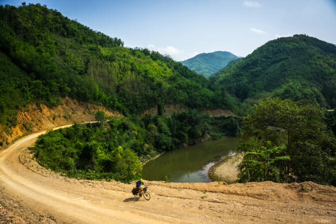 Nearing Luang Prabang, Will pushes up the dirt road along the Xuang River in Laos (photo credit: Kyle Seewald Hemes)