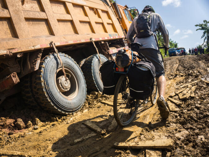 Will wades through the muck that has caught these heavy duty Chinese trucks after a rainstorm in Oudomxay province, Laos (image credit: Kyle Seewald Hemes)