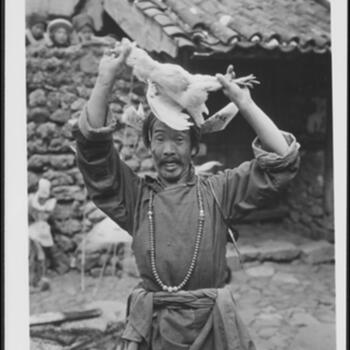 Naxi Llü-bu in a trance wearing a red turban with prayer papers and offering a chicken near Lijiang 1931