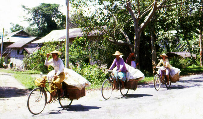 Dai women cycling home from the fields west of Ruili