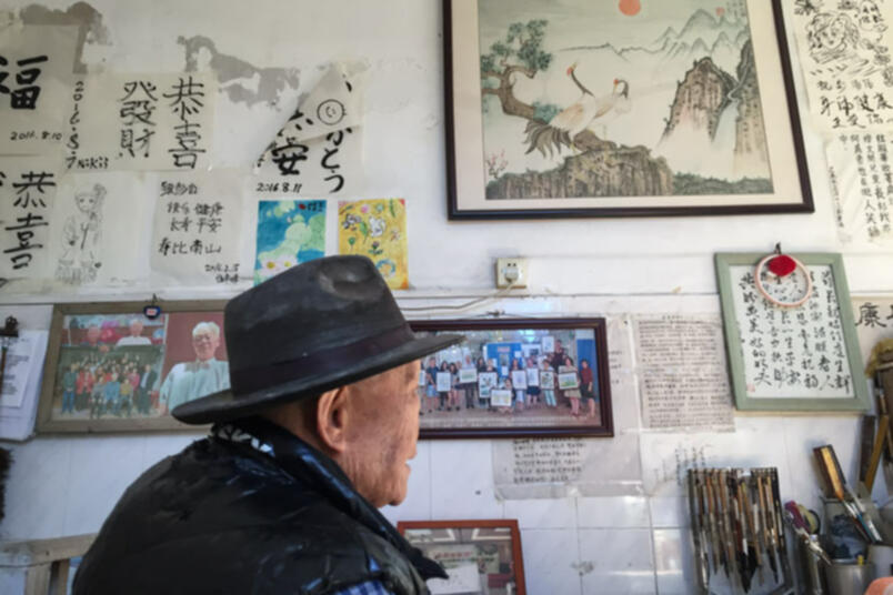 Peng Haidi poses for a photo in front of a wall with souvenirs from visitors at Si'an Hospital in Dongguan, Guangdong province, January 25, 2019 (Image credit: Cai Yiwen/Sixth Tone)