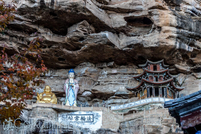 Statues of the Laughing Buddha and Guanyin under the cliffs of Baoxiang Temple